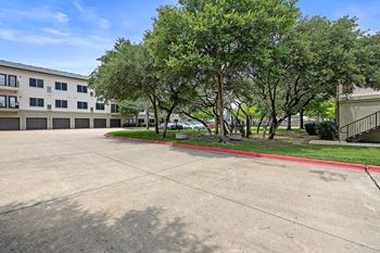 a parking lot with trees and a building in the background at Artisan Apartments & Shops, Texas, 78729